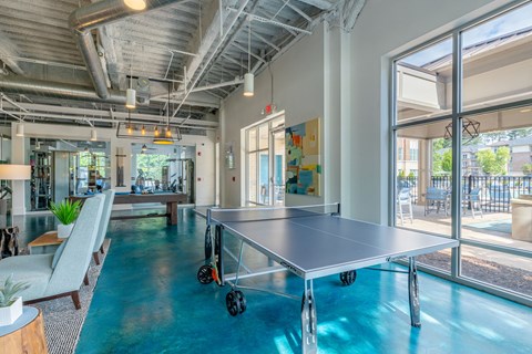 A ping pong table is in the middle of a room with a blue floor.