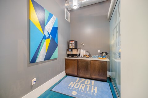 A blue and yellow painting hangs on a wall above a wooden cabinet.