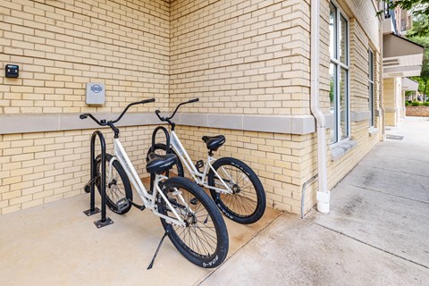 Two bicycles are parked next to a brick wall.