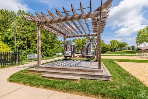 A wooden pergola structure with a metal sculpture in the middle.