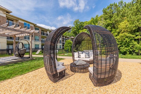 A modern outdoor seating area with two large woven structures and a small table.