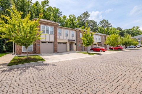 A row of townhouses with a red car parked in front of the first one.