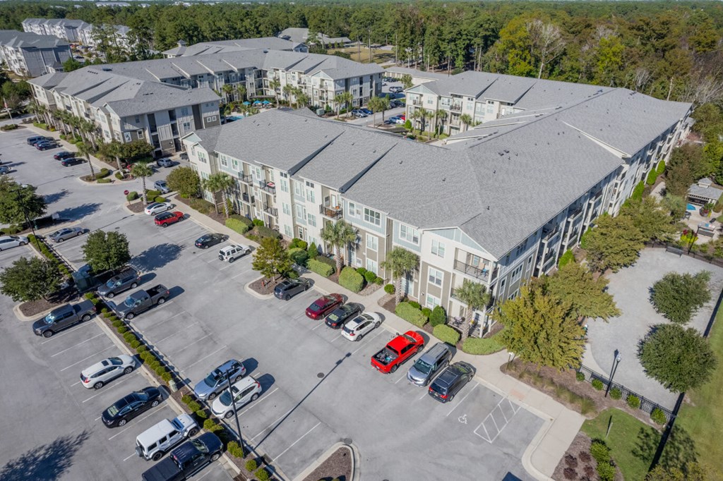 an aerial view of an apartment complex with parking lot and cars