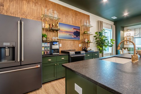 A modern kitchen with dark green cabinets and a wooden backsplash.