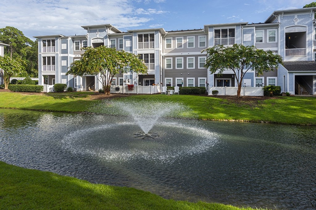 a fountain in a pond in front of an apartment building