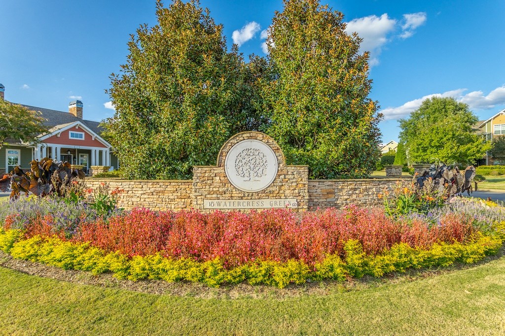 a retaining wall with a sign and flowers in front of a house