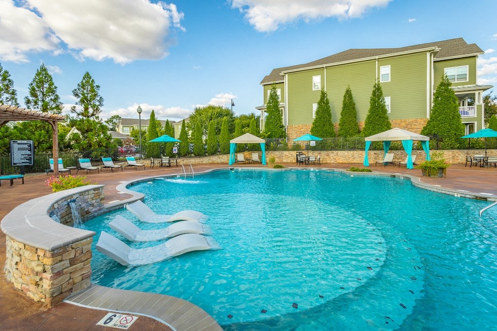 a resort style pool with lounge chairs and umbrellas