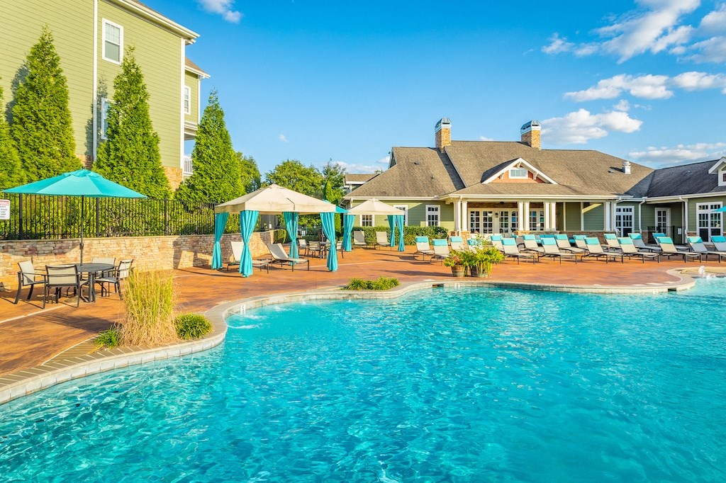 a resort style pool with lounge chairs and umbrellas