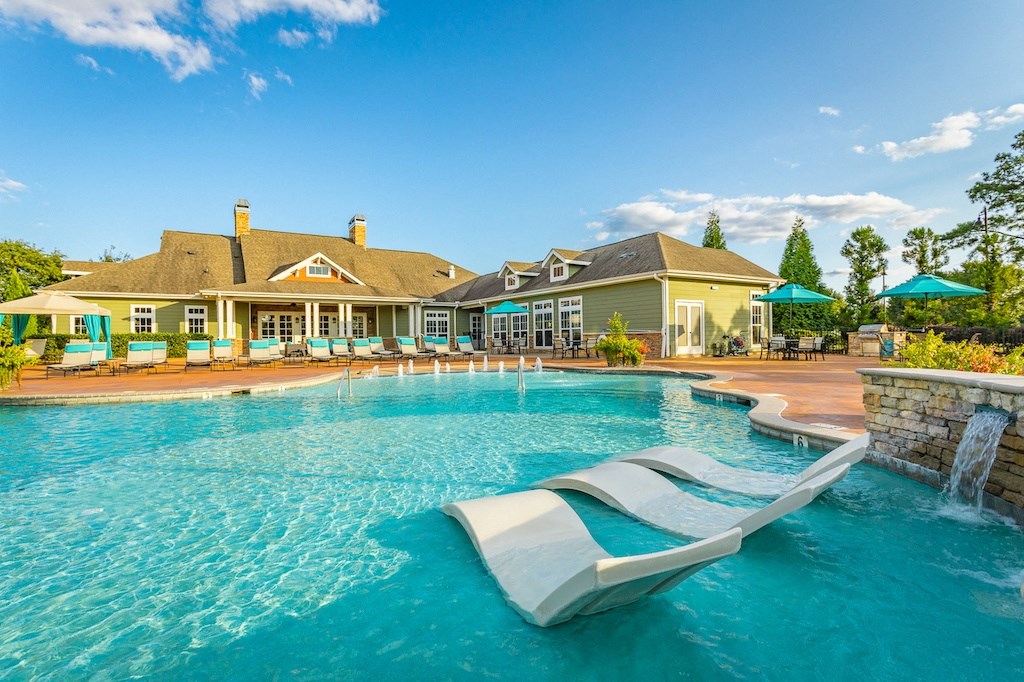 a pool with a lazy river and lounge chairs with umbrellas in the background
