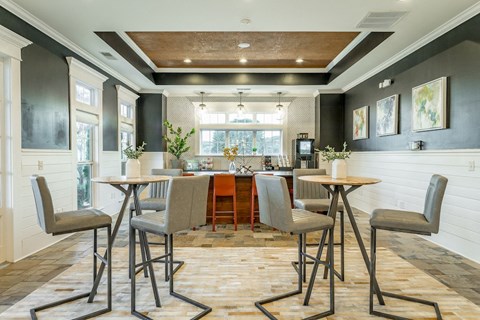 a dining area with tables and chairs and a kitchen in the background