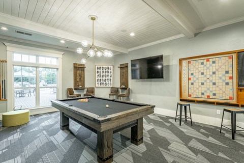A game room with a billiards table and a flat screen tv in the clubhouse at 18 Watercress Green apartments in Huntsville, AL.