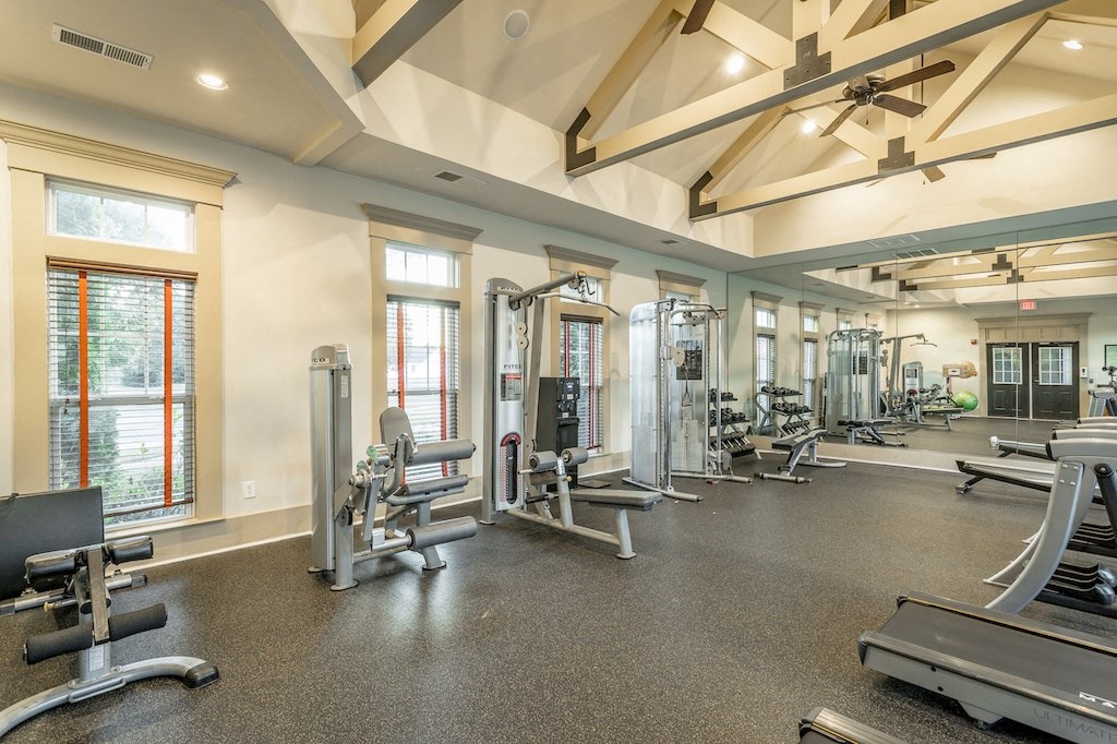a gym with cardio equipment and windows