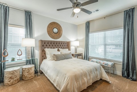 A bedroom with a bed and two windows at 18 Watercress Green apartments in Huntsville, AL.
