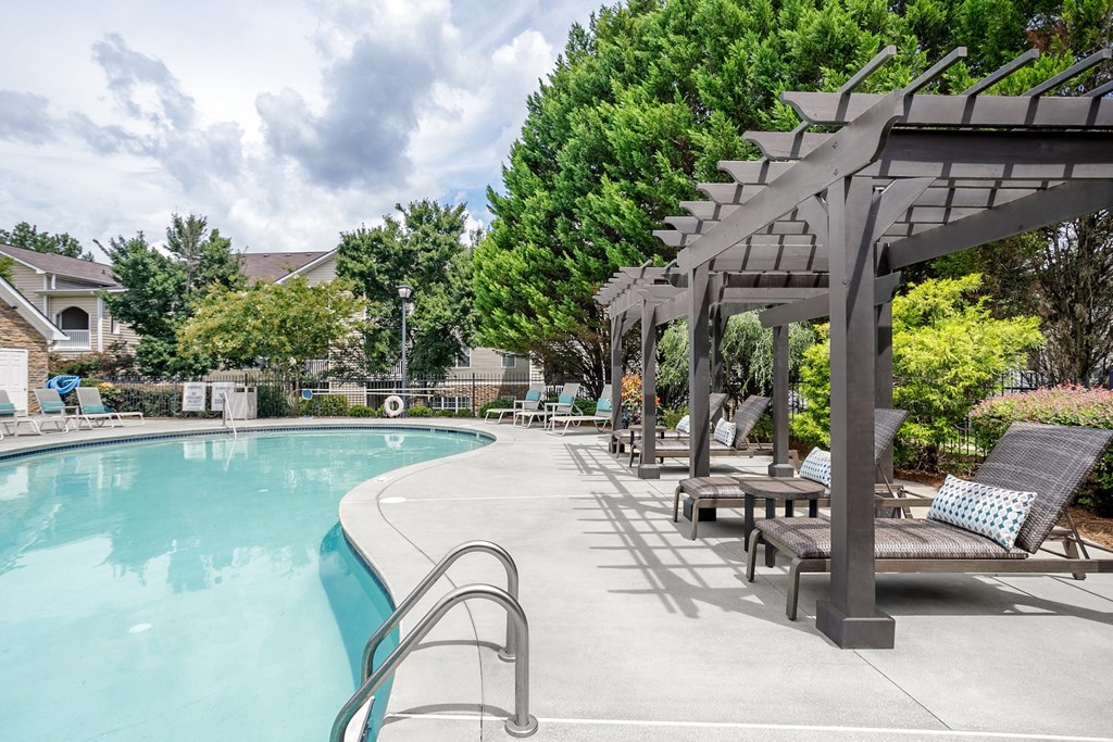 a swimming pool with lounge chairs and a poolside pavilion