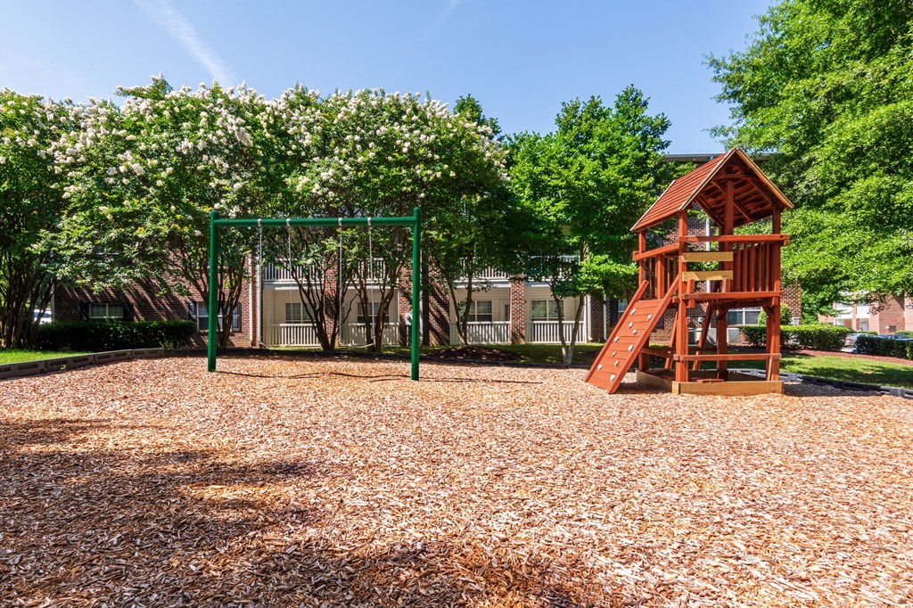 a playground with a swing set and a tree house