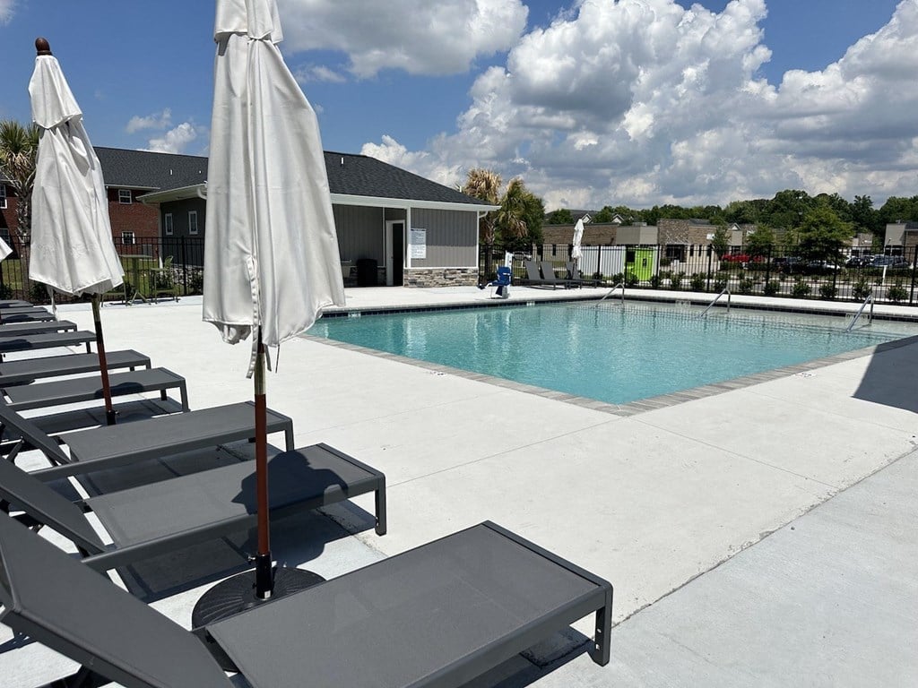 a swimming pool with chairs and umbrellas next to a building