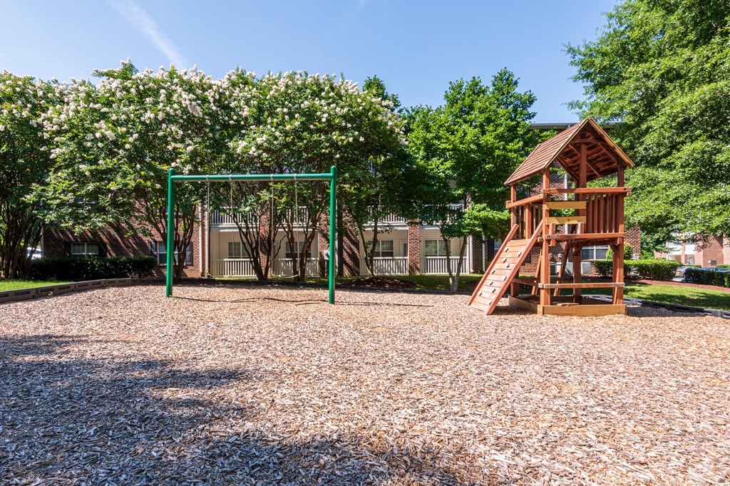 a playground with a swing set and a tree house