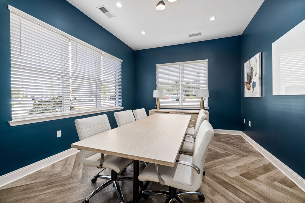 a conference room with a long wooden table and white chairs