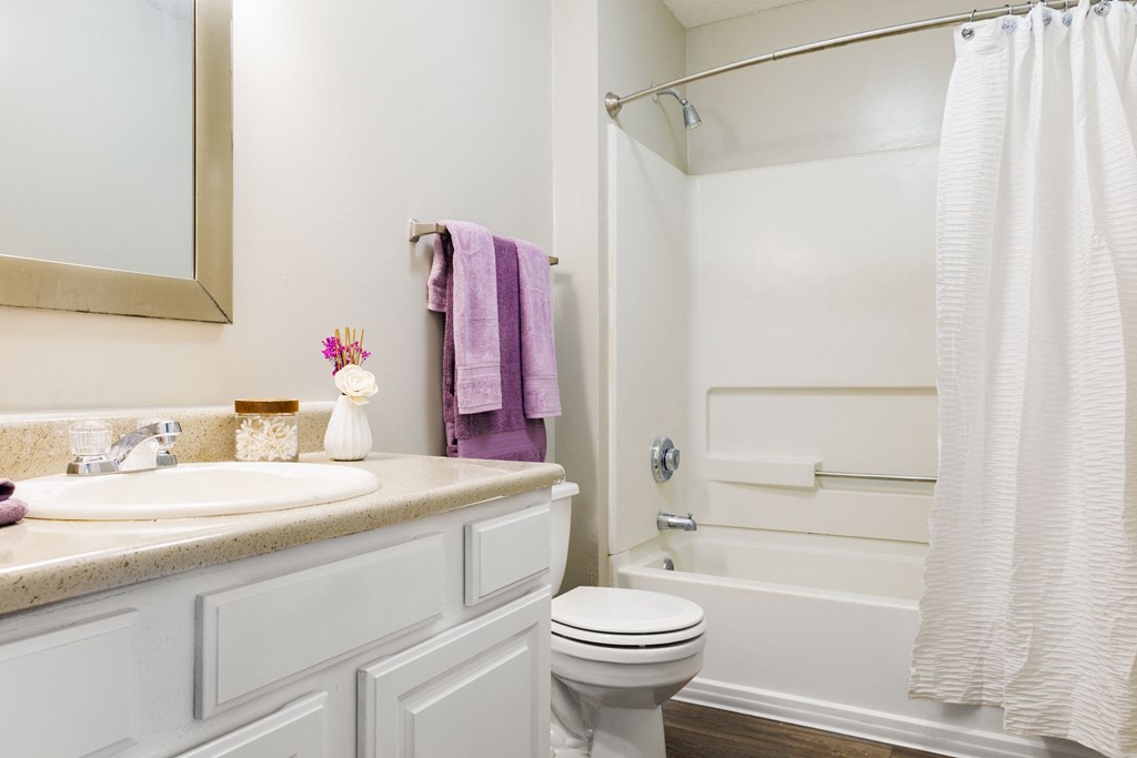 a bathroom with a white bathtub and a white sink with a purple towel