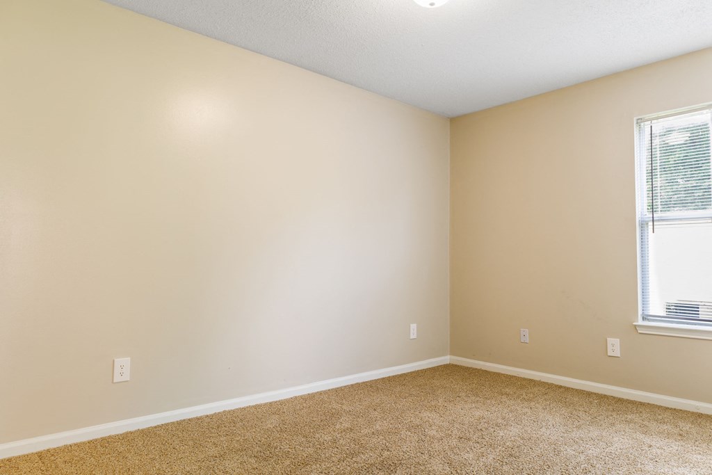 a bedroom with beige walls and a window