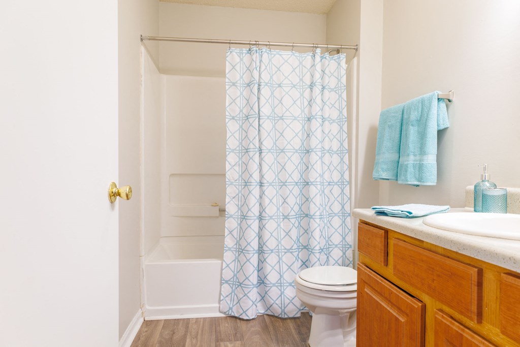 a bathroom with a white toilet next to a shower with a blue shower curtain