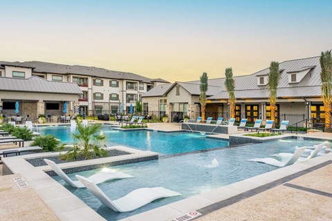 a swimming pool with chairs and buildings in the background