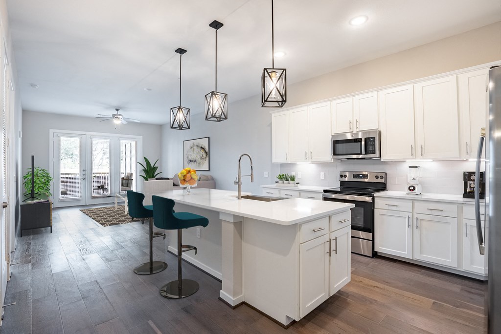 an open kitchen and living room with white cabinets and a white counter top