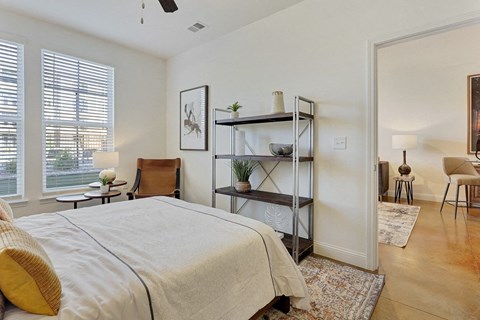 A bedroom with a bed, chair, and shelves.