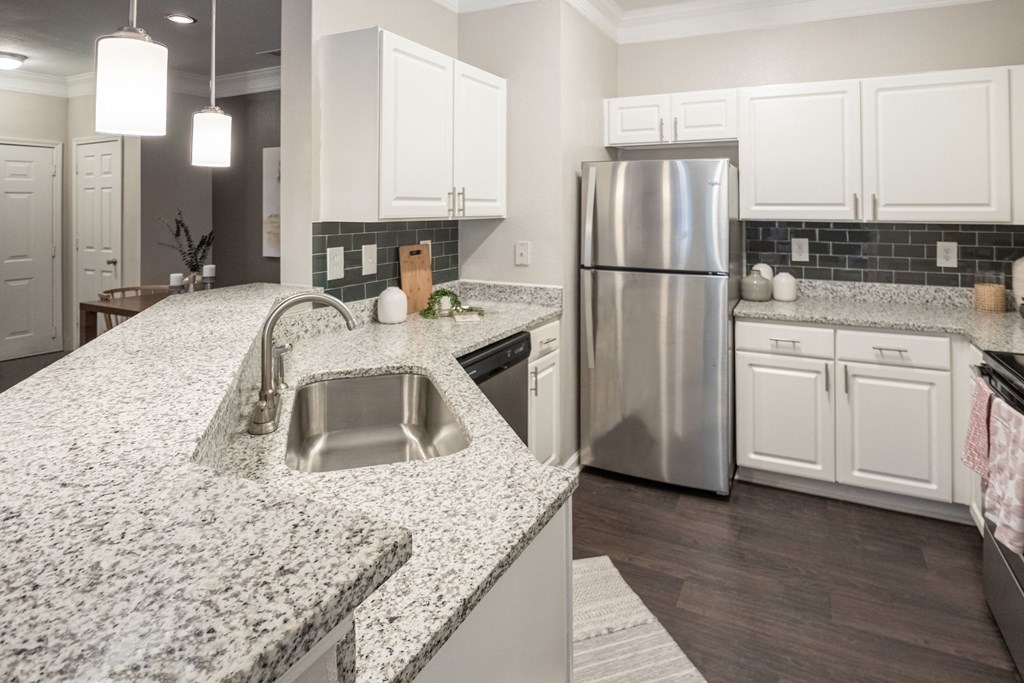 a kitchen with granite counter tops and a stainless steel refrigerator