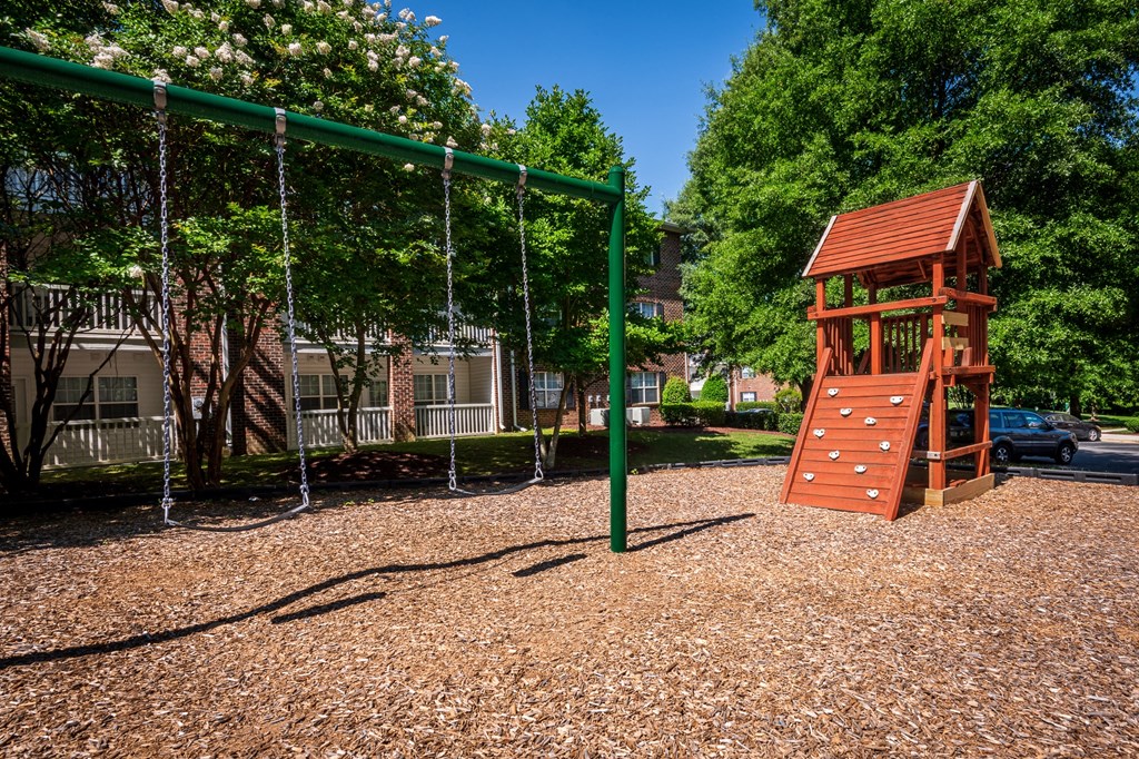 a playground with a swing set and a tree house