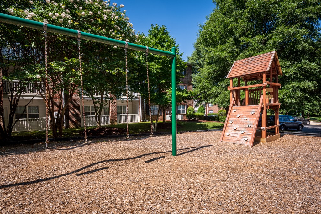 a playground with a swing set and a tree house