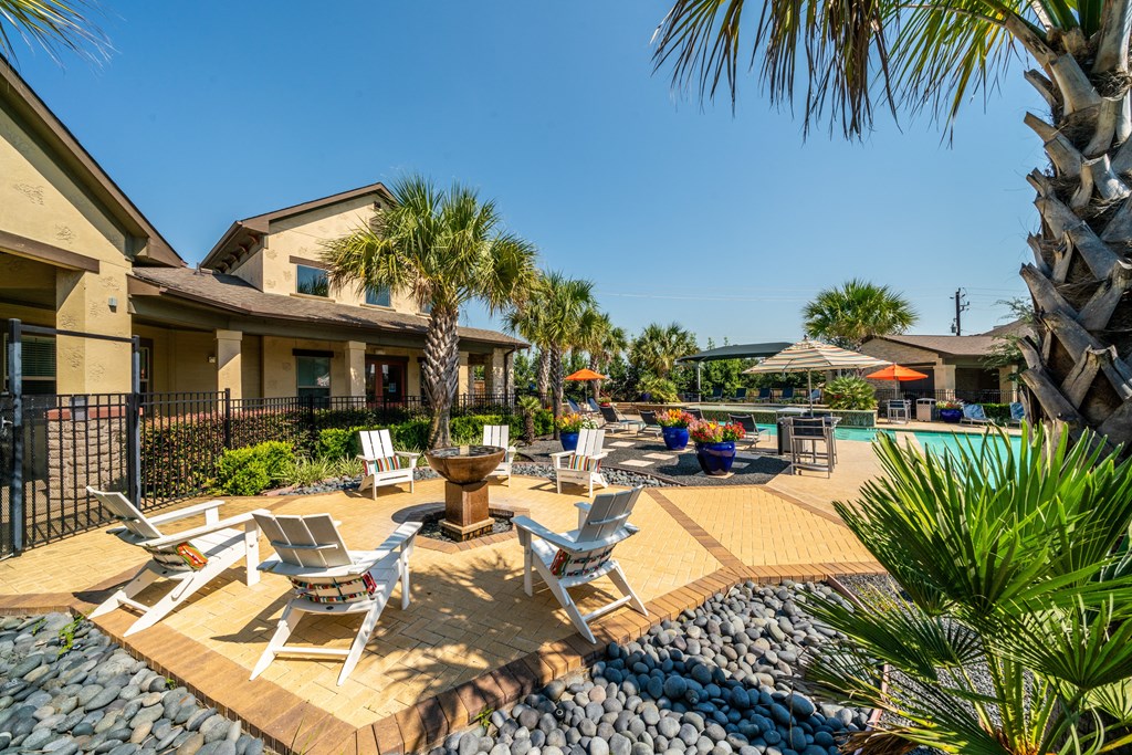 a backyard with a pool and chairs and palm trees