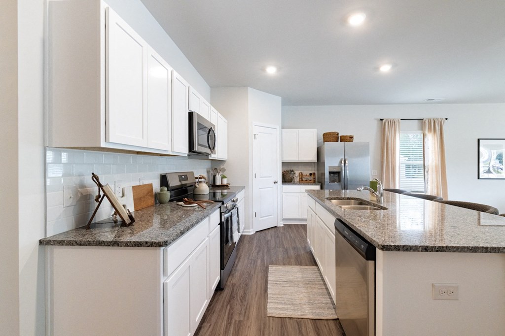 an open kitchen with white cabinets and granite counter tops