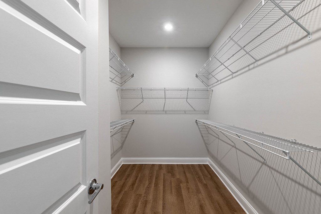 a spacious closet with white walls and a wood floor