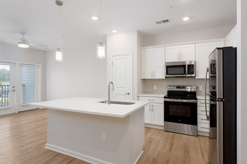 A modern kitchen with a white island and stainless steel appliances at Evolve Holly Ridge Apartments in Holly Ridge, NC.