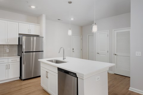 A modern kitchen with white cabinets and a stainless steel refrigerator at Evolve Holly Ridge Apartments in Holly Ridge, NC.
