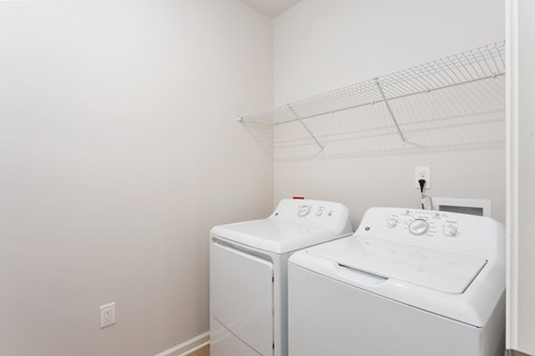 A white washing machine and dryer in a small laundry room. at Evolve Holly Ridge Apartments in Holly Ridge, NC at Evolve Holly Ridge Apartments in Holly Ridge, NC