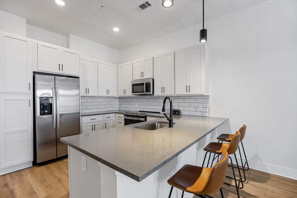 Interior Kitchen with a Refrigerator, Microwave, Sink and Barstools.
