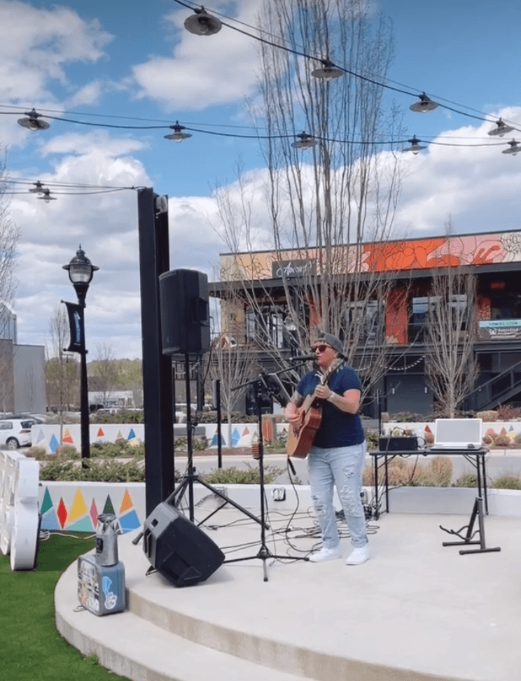 a man playing guitar on a stage in front of a building