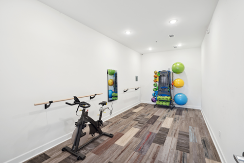 a gym with exercise equipment and a white room with white walls and wood floors
