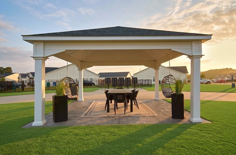 A white gazebo with a table and chairs is set up in a grassy area.