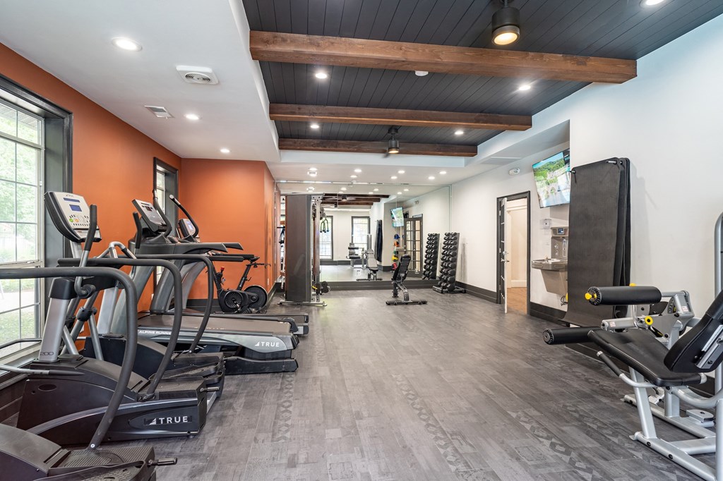 a gym with cardio machines and weights on a wooden floor
