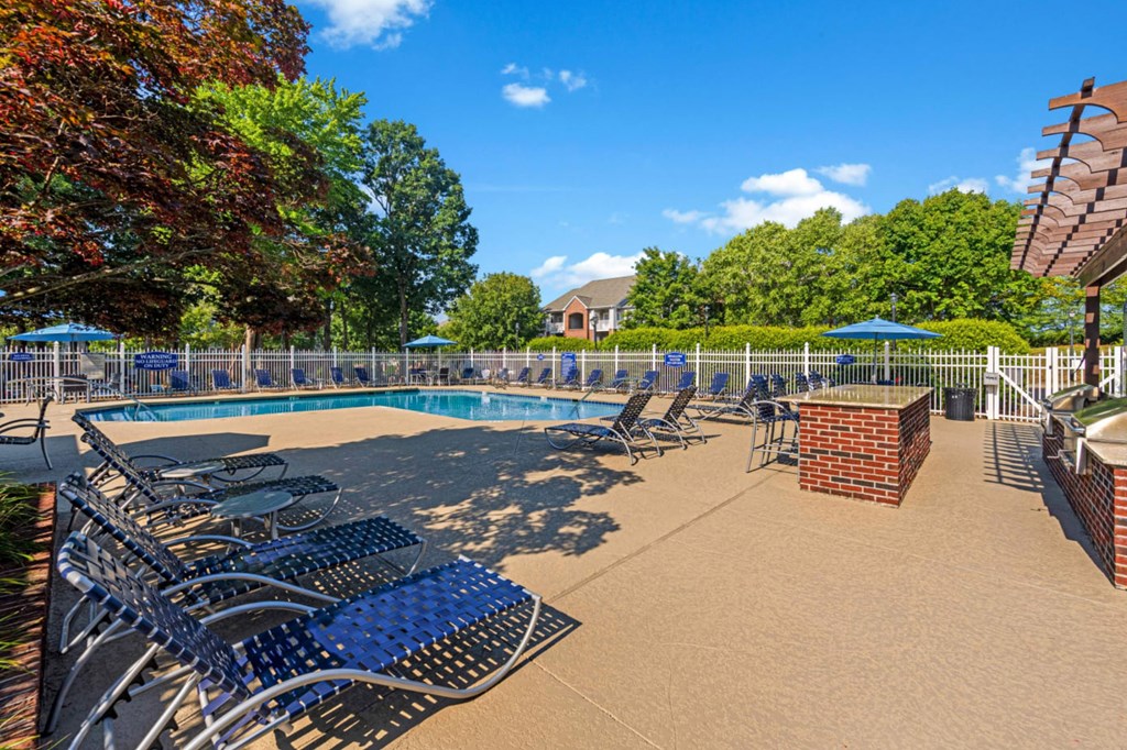 a swimming pool with blue lounge chairs and umbrellas