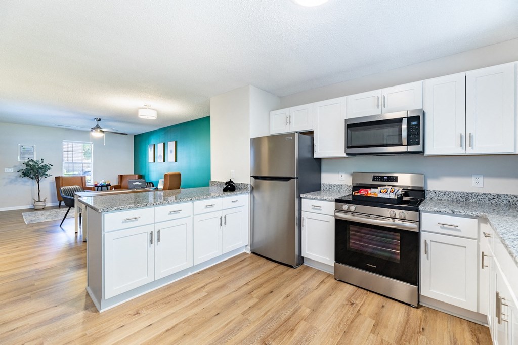 A kitchen with white cabinets and a stainless steel refrigerator.