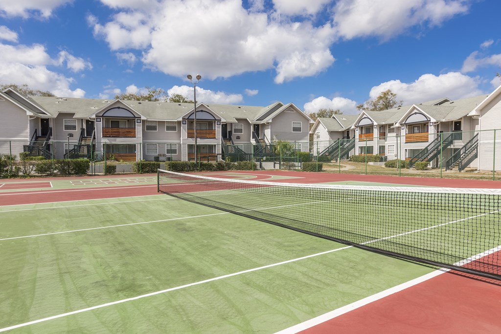 a tennis court with apartments in the background
