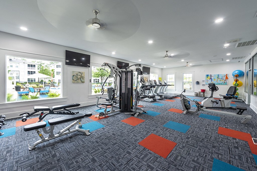 a gym with weights and cardio equipment in a building with windows