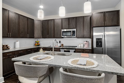A modern kitchen with dark brown cabinets and a granite countertop.