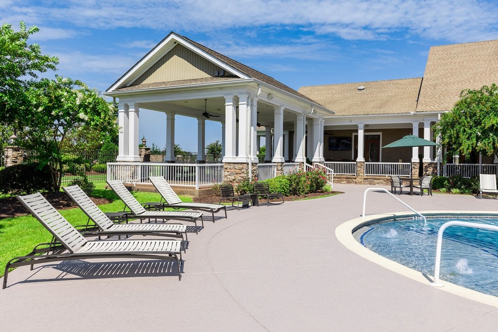 a pool and lounge chairs in front of a house