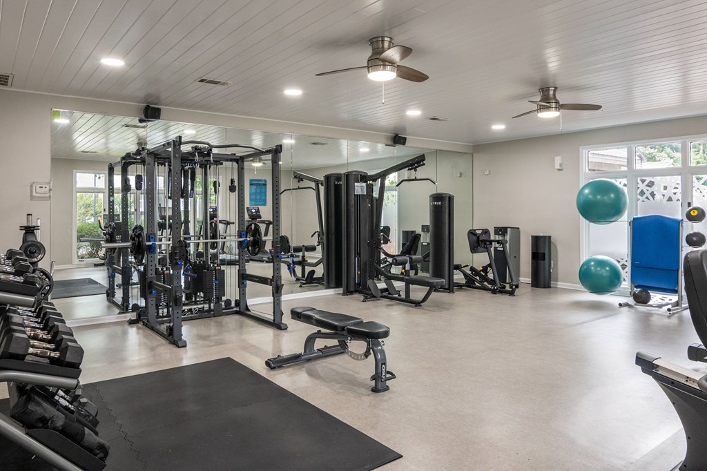 A spacious gym with a variety of equipment and a ceiling fan.