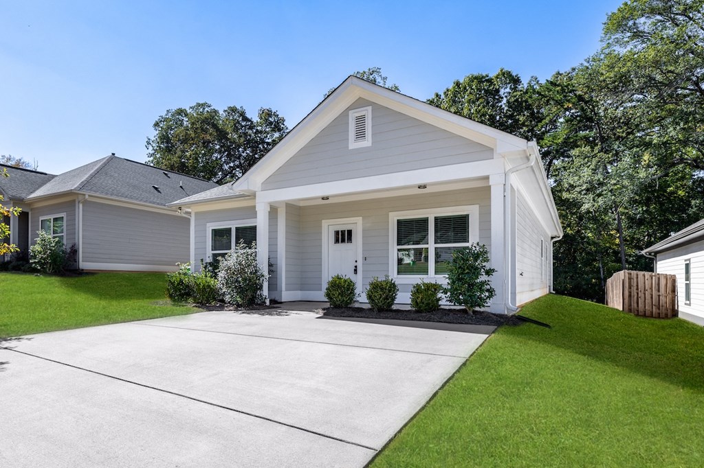 A house with a grey roof and white walls has a driveway in front.